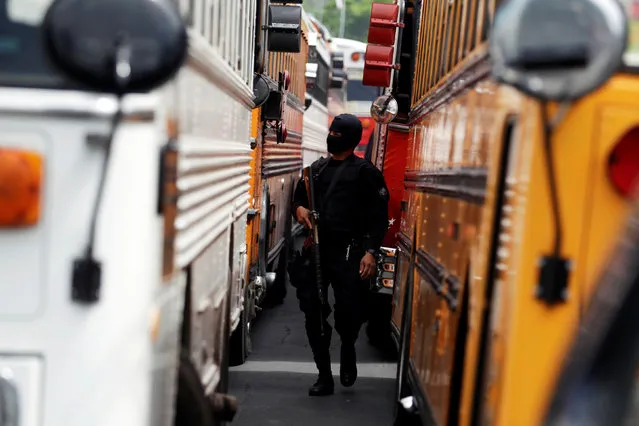 A Salvadoran policeman guards buses as 1282 members of the Barrio 18 gang are transferred from the cojutepeque jail in Cojutepeque, El Salvador June 16, 2016. (Photo by Jose Cabezas/Reuters)