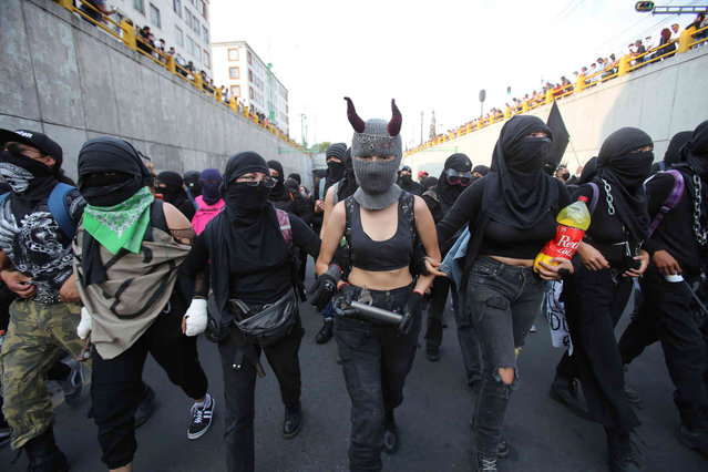 The Black Block walk during a march in remembrance of the 1968 Tlatelolco student massacre, in Mexico City, Saturday, October 2, 2021. Mexico commemorated the 53rd anniversary of the massacre where students and civilians were killed by the military and police. (Photo by Ginnette Riquelme/AP Photo)