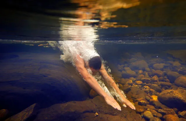 Russell Norris, 15, of Tylertown, Miss., dives into the chilly Swift River at Coos Canyon in Byron, Maine, on Jule 11, 2014. The canyon is considered one of the premier swimming holes in the U.S. (Photo by Robert F. Bukaty/Associated Press)