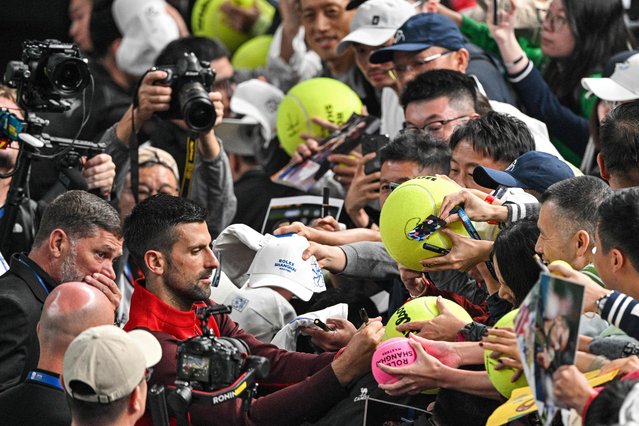 Serbia's Novak Djokovic signs autographs for fans at the end of his men's singles match against Czech Republic's Jakub Mensik at the Shanghai Masters tennis tournament in Shanghai on October 11, 2024. (Photo by Hector Retamal/AFP Photo)