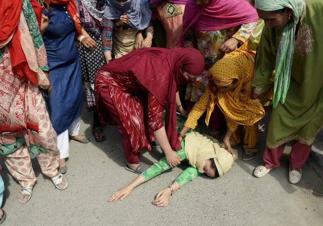 A Kashmiri woman lies on the ground after fainting fainted during the funeral procession of slain militant Yawar Nissar at Shipora in Anantnag, South of Srinagar, on August 4, 2017. Two Indian soldiers and two rebels were killed in armed clashes on August 3, officials said, in another day of bloodshed in Kashmir where tensions are high following the death of a prominent militant. The rebels were killed in Kulgam, south of the main city of Srinagar in Indian- administered Kashmir, when they walked into an ambush laid by Indian soldiers. (Photo by Tauseef Mustafa/AFP Photo)