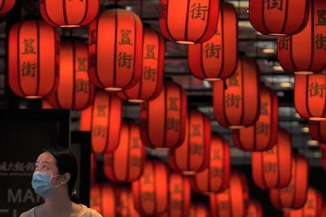 A woman wearing a face mask looks as she walks through red lanterns on display at a subway station in Beijing, Sunday, June 26, 2022. (Photo by Andy Wong/AP Photo)