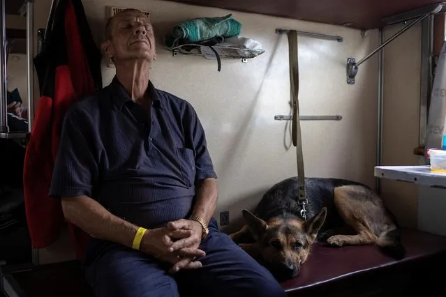 A man with his dog sits in a train to Dnipro and Lviv during an evacuation of civilians from war-affected areas of eastern Ukraine, amid Russia's invasion of the country, in Pokrovsk, Donetsk region, Ukraine, June 25, 2022. (Photo by Marko Djurica/Reuters)
