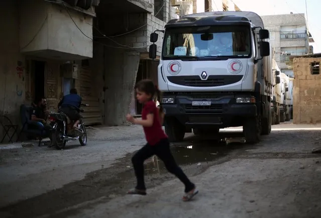 A convoy of Syrian Red Crescent trucks carrying aid drives through Zamalka, a besieged rebel-held town east of the Syrian capital Damascus, on June 29, 2016. The convoy entered the besieged Syrian towns of Zamalka and Erbin near Damascus, the first aid delivered to them since 2012, the International Committee of the Red Cross told AFP. ICRC added it was delivering 37 trucks of aid in partnership with the United Nations and Syrian Arab Red Crescent. The convoy includes food parcels, wheat flower, and hygiene kits for the 20,000 people living in the besiged towns. (Photo by Amer Almohibany/AFP Photo)