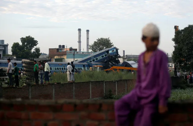 A boy sits on a wall near derailed passenger train coaches, at the site of an accident in Khatauli, in the northern state of Uttar Pradesh, India August 20, 2017. (Photo by Adnan Abidi/Reuters)