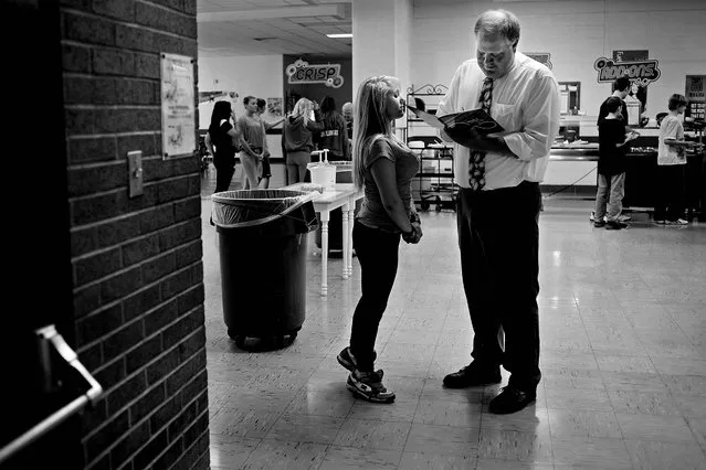 Photojournalist Of The Year (Small Markets). One of 32 pictures in the portfolio of Sean Proctor, of the Midland Daily News:  Standing on her tip-toes to get a better view, Brandi Porter watches as principal Steve Poole writes in her yearbook during eighth grade lunch at Central Middle School in Midland, Mich. Population shrinkage and declining enrollment led to the school's shutdown, with most students and faculty transferring to other schools in the district. (Photo by Sean Proctor)