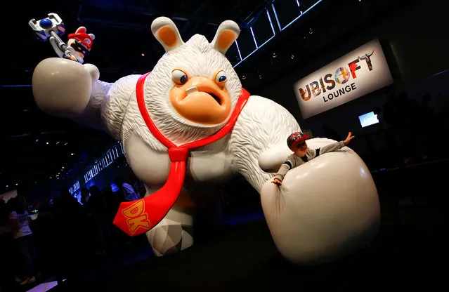 A boy poses for a picture, inside the hand of a Rabbid Kong figure at the world's largest computer games fair, Gamescom, in Cologne, Germany August 23, 2017. (Photo by Wolfgang Rattay/Reuters)