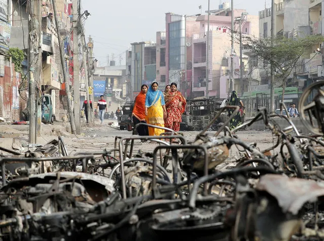 Women walk past charred vehicles in a riot affected area following clashes between people demonstrating for and against a new citizenship law in New Delhi, India, February 27, 2020. (Photo by Adnan Abidi/Reuters)