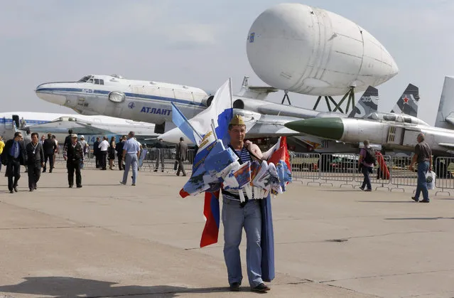 A vendor sells souvenirs walking in front of an exhibition of old and rare airplanes  on the airfield of MAKS-2015, the International Aviation and Space Show in the city of Zhukovsky outside Moscow, Russia, 26 August 2015. (Photo by Sergei Chirikov/EPA)