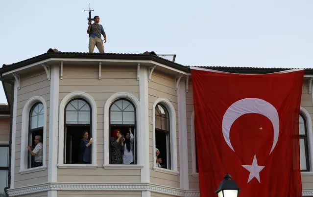 People try to take pictures of Turkish President Tayyip Erdogan walking through the crowd of supporters, as a security officer stands on the roof in Istanbul, Turkey, July 16, 2016. (Photo by Murad Sezer/Reuters)