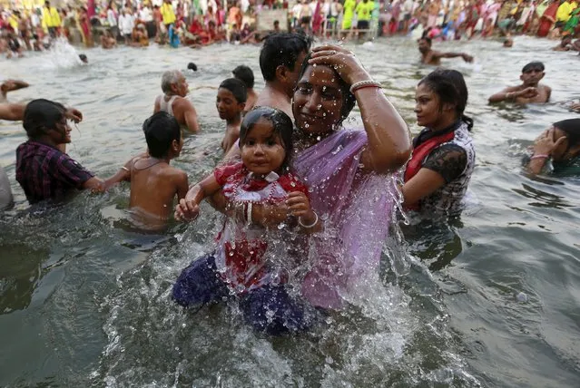 A Hindu devotees takes a dip with her daughter in the Godavari river during Kumbh Mela or the Pitcher Festival in Nashik, India, August 28, 2015. (Photo by Danish Siddiqui/Reuters)