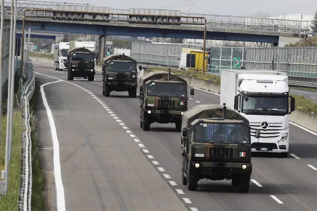 Military trucks moving coffins of deceased people line up on the highway next to Ponte Oglio, near Bergamo, one of the areas worst hit by the coronavirus infection, on their way from Bergamo cemetery to a crematory in some other location as the local crematory exceeded its maximum capacity, Thursday, March 26, 2020. (Photo by Luca Bruno/AP Photo)