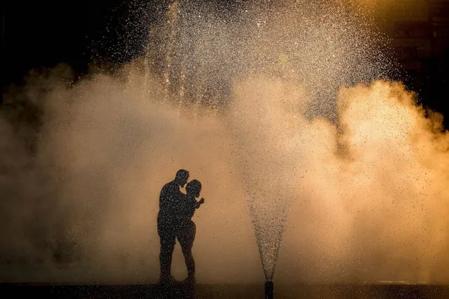 A couple hug near a city fountain at sunset in Bucharest, Romania, Wednesday, July 20, 2022. A severe heatwave is forecasted for the coming days across Romania. (Photo by Vadim Ghirda/AP Photo)
