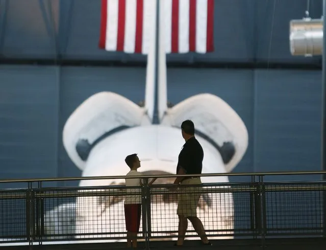 A father and son look at the space shuttle orbiter Discovery on display at the Udvar-Hazy Smithsonian National Air and Space Annex Museum in Chantilly, Virginia August 28, 2015. Shuttle Discovery had 27 years of service and flew 39 times before being retired in 2011. (Photo by Gary Cameron/Reuters)