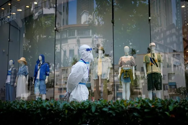 A worker in a protective suit walks past a shop, amid new lockdown measures in parts of the city to curb the coronavirus disease (COVID-19) outbreak in Shanghai, China on June 15, 2022. (Photo by Aly Song/Reuters)