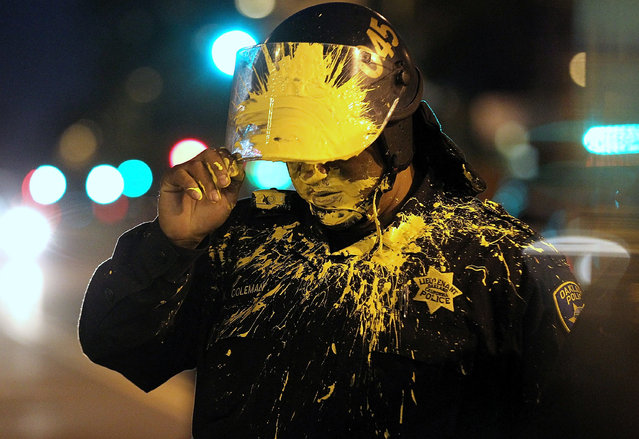 An Oakland police officer pauses after being hit in the face with paint as officers advanced on Occupy protesters blocking an intersection during a May Day demonstration on May 1, 2012 in Oakland, California. (Photo by Justin Sullivan/Getty Images)