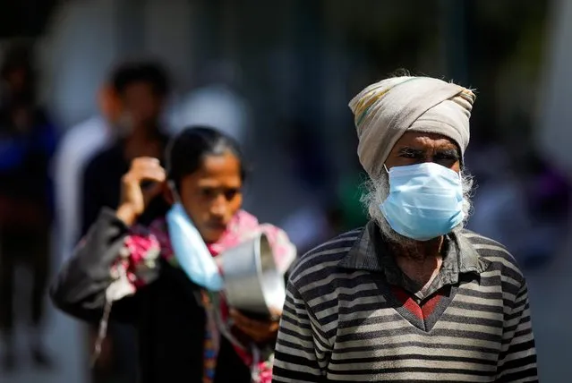 People wearing protective masks queue for food inside a sports complex turned into a shelter, during a 21-day nationwide lockdown to slow the spread of the coronavirus disease (COVID-19), in New Delhi, India, April 4, 2020. (Photo by Adnan Abidi/Reuters)