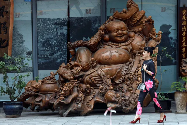 A woman walks past a laughing Buddha sculpture near the venue where the G20 Finance Ministers and Central Bank Governors Meeting will be held over the weekend in Chengdu in Southwestern China's Sichuan province, July 22, 2016. (Photo by Ng Han Guan/Reuters)