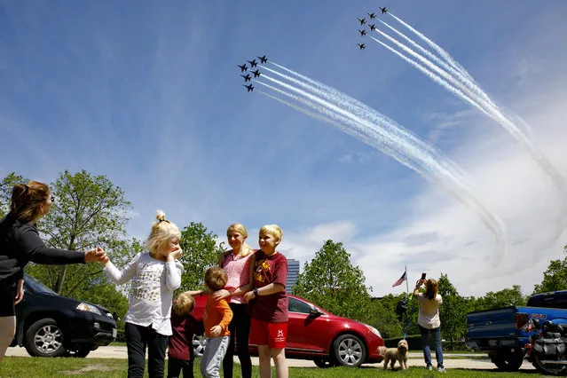The Ferry family, from Chantilly, Va., who were in the middle of taking a family photograph, are surprised by a second fly over by the Blue Angels and Thunderbirds, in a “salute to frontline COVID-19 responders”, as seen near the U.S. Marine Corps War Memorial that depicts a flag raising over Iwo Jima, in Arlington, Va., Saturday, May 2, 2020. (Photo by Jacquelyn Martin/AP Photo)