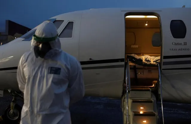 A healthcare worker on protective clothing reacts in front of the body of Laureano Ferraz, 78, a Wanano indigenous man who passed away due to COVID-19, after arriving by an ICU jet from Sao Gabriel da Cachoeira to Manaus, Brazil, May 18, 2020. (Photo by Bruno Kelly/Reuters)