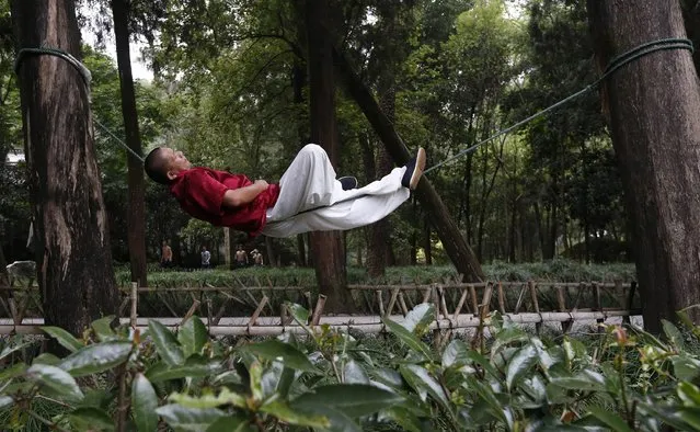 Liang Yanguo, 51, naps as he lies on a rope tied between two trees, as a form of martial arts practice, at a park in Huangyan district of Taizhou, Zhejiang province September 18, 2014. Liang was training in martial arts and free combat until he was diagnosed with late stage throat cancer three years ago. After having surgery, he invented the rope method as a more relaxed way to continue practicing martial arts and keep his body healthy, local media reported. (Photo by William Hong/Reuters)