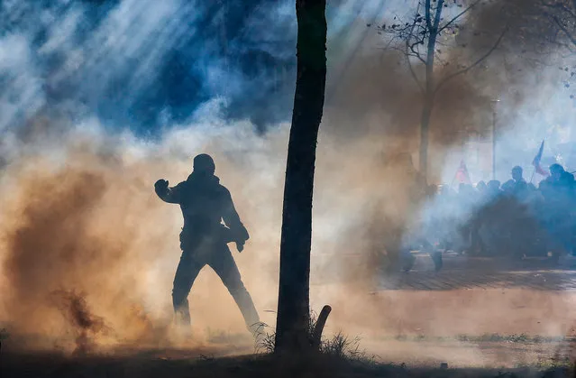 A protester is silhouetted in teargas during clashes with riot police during a demonstration against the French government's labor reforms in Paris, France, 21 September 2017. Workers are staging protests around the country in France's major cities – becoming a weekly fixture – days before president Emmanuel Macron's reform is set to become law. Additionally, an estimated 2,000 members of the CRS riot police, usually tasked with policing such street protests, have taken the day off citing “health reasons”, to protest the fiscalization of their travel bonuses. (Photo by Etienne Laurent/EPA/EFE)