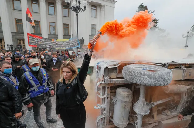 An activist lights a smoke grenade next to a turned-over vehicle during a rally outside the Parliament building in Kiev, Ukraine, 05 June 2020. Ukrainians gathered demanding the resignation of the Interior Minister Arsen Avakov after a series of criminal cases with the participation of policemen in Ukraine. (Photo by Sergey Dolzhenko/EPA/EFE)