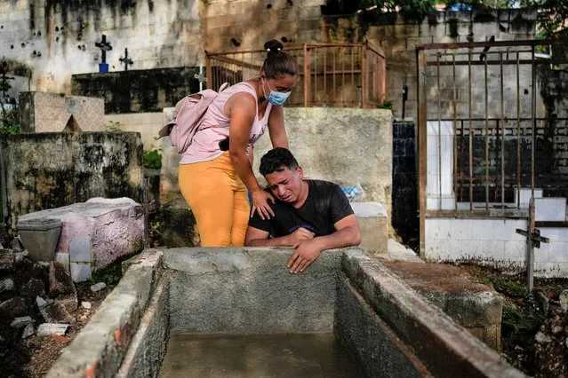 Johaniet Cartaya, left, and her brother Jorge Cartaya mourn after they buried in the same grave their mother Yanet Rivas and their aunt Aimara Navas in Las Tejerias, Venezuela, Wednesday, October 12, 2022. The sisters were among dozens who died when a landslide caused by heavy rains swept Las Tejerias on the night of Oct. 9. (Photo by Matias Delacroix/AP Photo)