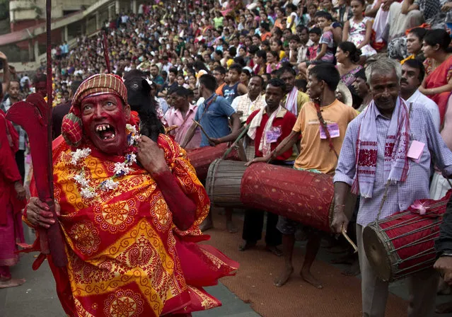 A Hindu priest, face smeared with color and sacrificial blood, carries a goat over his shoulder for sacrifice during the Deodhani festival at the Kamakhya Hindu temple in Gauhati, India, Thursday, August 18, 2016.  The festival is held to worship the serpent Goddess where goats and pigeons are commonly offered as sacrifice in belief that participants receive supernatural power from goddess Kamakhya. (Photo by Anupam Nath/AP Photo)