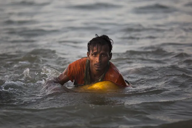 In this November 4, 2017, file photo, Rohingya Muslim Abdul Karim, 19, uses a yellow plastic oil container as a flotation device as he swims the Naf river while crossing the Myanmar-Bangladesh border in Shah Porir Dwip, Bangladesh. Rohingya Muslims escaping the violence in their homeland of Myanmar are now so desperate that some are swimming to safety in neighboring Bangladesh, even if they have never been in the water before. (Photo by Bernat Armangue/AP Photo)