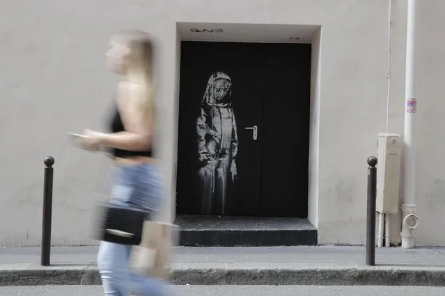 In this file photo taken on June 25, 2018 a woman walks past a recent artwork by street artist Banksy in Paris on a side street to the Bataclan concert hall where a terrorist attack killed 90 people on Novembre 13, 2015. The stolen Banksy work has been found in Italy, AFP reports on June 10, 2020. (Photo by Thomas Samson/AFP Photo)