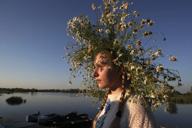 A girl wears a flower wreath during Ivan Kupala Day celebrations held by the Pripyat River in the town of Turauin Gomel Region, Belarus on July 6, 2020. Ivan Kupala Day, also known as Ivana-Kupala or Kupala Night, is a traditional pagan holiday celebrated in eastern Slavic cultures. Various rituals are traditionally performed on Kupala Night, including making flower wreaths, fortune-telling, jumping over bonfires, and burning a wheel-like effigy symbolizing the sun. (Photo by Natalia Fedosenko/TASS)
