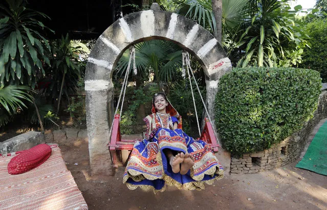 A girl dressed in traditional attire plays on a swing after taking part in rehearsals for the “garba” dance ahead of the Navratri festival in Ahmedabad September 21, 2014. (Photo by Amit Dave/Reuters)