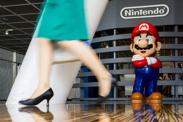A woman walks past a figure of “Mario”, a character in Nintendo's Mario Bros. video games, at a Nintendo centre in Tokyo July 29, 2015. (Photo by Thomas Peter/Reuters)