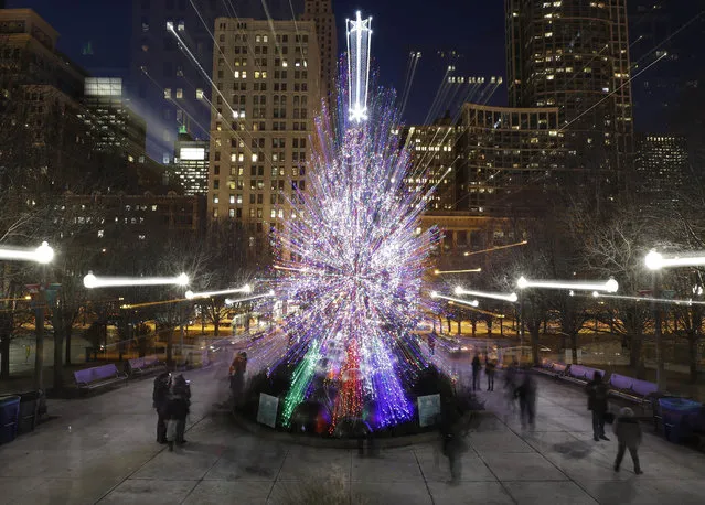 Tourists walk past the Millennium Park Christmas tree in a timed exposure with a zoom lens Thursday, December 14, 2017, in Chicago. (Photo by Charles Rex Arbogast/AP Photo)