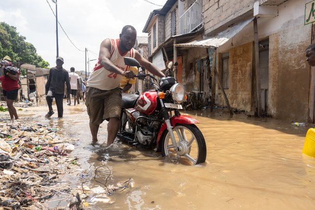 A man pushes his motorcycle in a flooded street in Kinshasa, Democratic Republic of Congo, 07 April 2025. At least 33 deaths have been recorded according to Ministry of the Interior during a flood of the Ndjili River bursting its banks in the city of Kinshasa. (Photo by Chris Milosi/EPA/EFE)