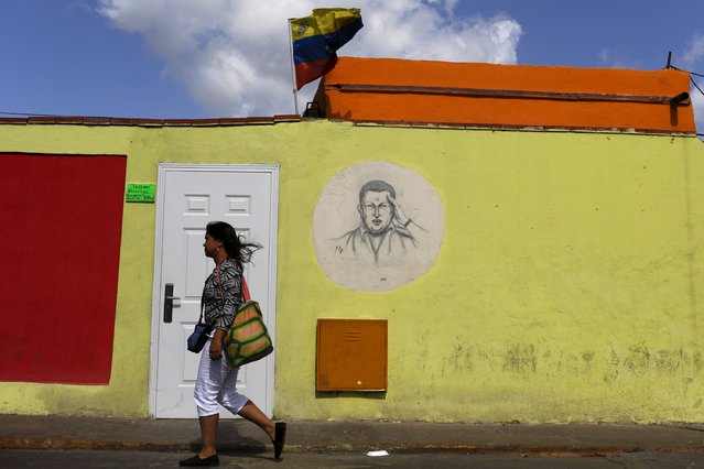 A woman walks past a mural depicting Venezuela's late president Hugo Chavez, during a ceremony to commemorate his 61st birthday at the 4F military fort in Caracas July 28, 2015. (Photo by Carlos Garcia Rawlins/Reuters)