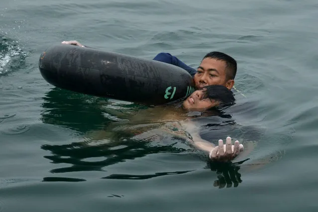 In this handout photograph released by the Indonesian Navy on October 13, 2015, an Indonesian Navy diver rescues helicopter crash survivor Fransiskus Subihardayan after he was found by the search and rescue team in Lake Toba, western Sumatra island on October 13, 2015. (Photo by AFP Photo/Indonesian Navy)