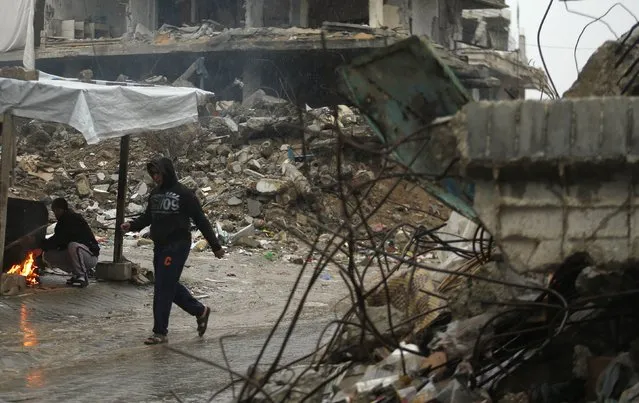 A Palestinian man walks past a house that witnesses said was destroyed by Israeli shelling during the most recent conflict between Israel and Hamas, on a rainy day in the east of Gaza City November 16, 2014. (Photo by Suhaib Salem/Reuters)