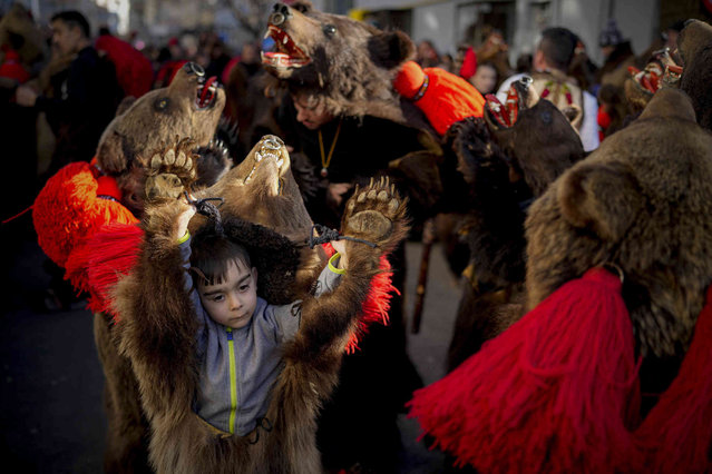Children wearing bear fur costumes dance during a parade in Comanesti, Romania, Friday, December 30, 2022. In pre-Christian rural traditions, dancers wearing colored costumes or animal furs, toured from house to house in villages singing and dancing to ward off evil. (Photo by Vadim Ghirda/AP Photo)