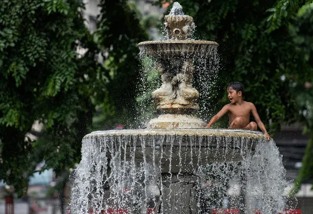 A boy plays in a water fountain at a public park in Manila, Philippines on August 3, 2017. (Photo by Noel Celis/AFP Photo)