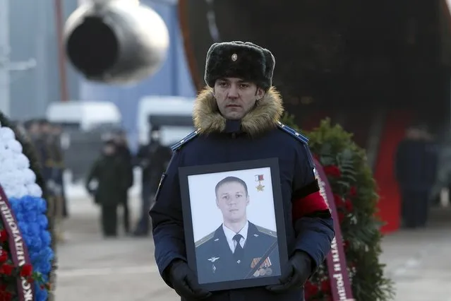 A Russian officer holds a portrait of Russian Roman Filipov, the pilot of the Su-25 jet who ejected after Syrian insurgents shot down his plane traded fire with militants on the ground and then blew himself up to avoid being captured, during a farewell service at Chkalovsky military airport, just outside Moscow, Russia, Thursday, February 8, 2018. (Photo by Vadim Savitsky/Pool Photo via AP Photo)