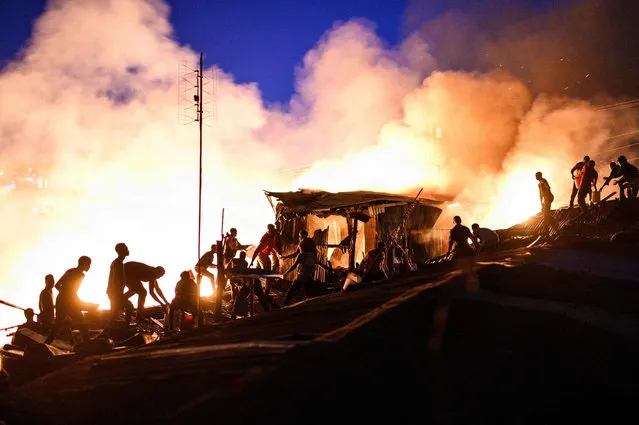 Residents of Kibera form a human-chain as they pass water to extinguish a fire that gutted shantees in the Maranatha area of the sprawling slum that started at dusk in Nairobi on October 14, 2020. About fifty families were left homeless by the inferno that spread unabated despite efforts to douse it using pails and jerrycans as firefighters were unable to access the area due to a lack of access roads. (Photo by Gordwin Odhiambo/AFP Photo)