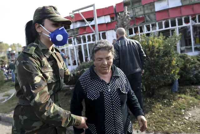 An Azerbaijani officer helps an elderly woman to leave a dangerous area after multiple rocket system shelling by Armenian forces in Barda, Azerbaijan, Wednesday, October 28, 2020. (Photo by Aziz Karimov/AP Photo)