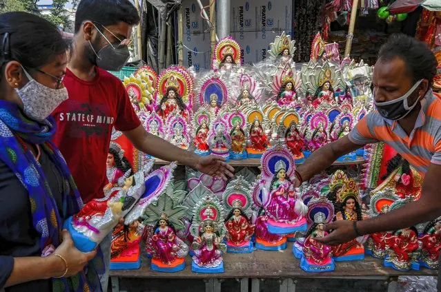 People buy clay idols of Laxmi, the Hindu goddess of wealth, ahead of Laxmi Puja festival in Kolkata, India, Thursday, October 29, 2020. India's confirmed coronavirus caseload surpassed 8 million on Thursday with daily infections dipping to the lowest level this week, as concerns grew over a major Hindu festival season and winter setting in. (Photo by Bikas Das/AP Photo)