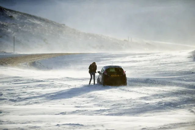 People push a car stuck on the A93 Braemar to Glenshee road as snow is forecast for much of the UK on December 8, 2014 in Glenshee, Scotland. The Met Office yellow “Be Aware” warning remains in place across the country, with drivers struggling with snow fall overnight. (Photo by Jeff J. Mitchell/Getty Images)