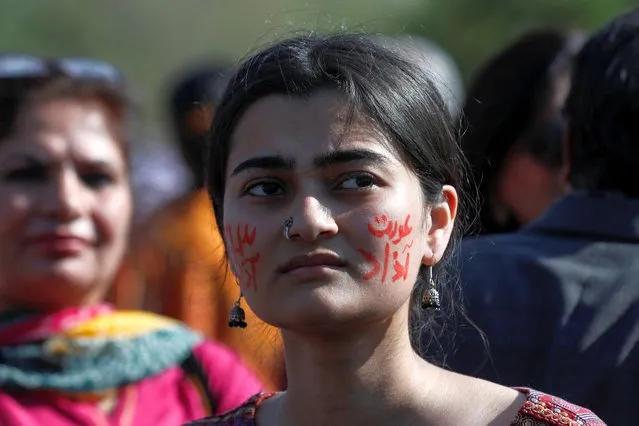 A woman, who has the words “Woman's Freedom” and “Social Freedom” painted on her cheeks, along with others, participate in "Aurat March" or “Women's March”, to mark International Women's Day, in Islamabad, Pakistan on March 8, 2023. (Photo by Akhtar Soomro/Reuters)