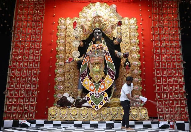 Man sanitises a “pandal” (a temporary platform), next to an idol of Hindu goddess Kali, ahead of the Kali Puja festival, amidst the spread of COVID-19 in Kolkata, India, November 12, 2020. (Photo by Rupak De Chowdhuri/Reuters)