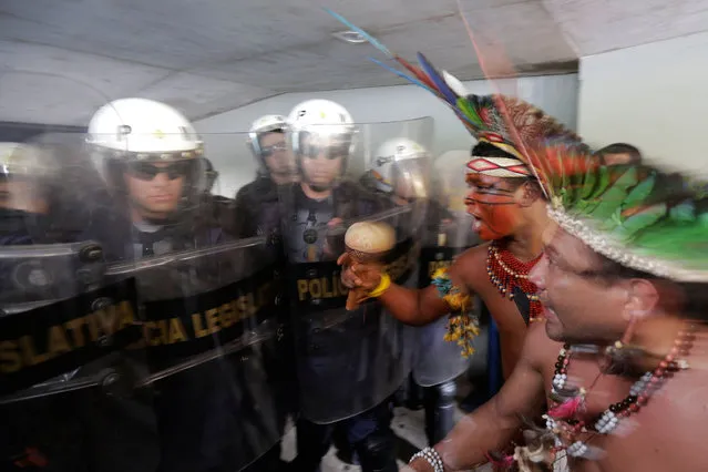 Indians from various tribes argue with police blocking them from entering the Chamber of Deputies where lawmakers are debating the authority to demarcate indigenous lands at Congress in Brasilia, Brazil, Tuesday, December 16, 2014. Brazil's indigenous don't agree with a proposed constitutional amendment that would allow Congress to decide their ancestral land's legal borders, in place of the Ministry of Justice with whom negotiations had already started years ago. (Photo by Eraldo Peres/AP Photo)