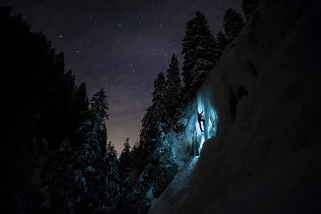 In this February 14, 2018 photo Pierre, a member of Team Arnicare, climbs an Ice Cascade during a night-time training session under a stary night near La Lecherette in the Hongrin region, in canton Vaud, Switzerland. (Photo by Anthony Anex/Keystone via AP Photo)